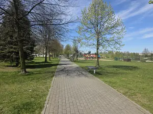 Brukowana aleja parkowa, po prawej stronie plac zabaw dla dzieci