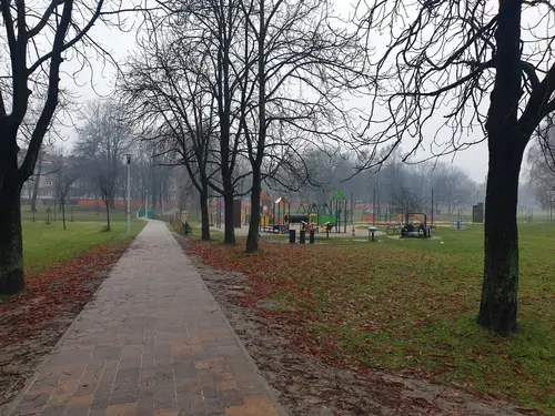 W tle plac zabaw i siłownia plenerowa