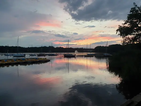 Widok na zacumowane żagl&oacute;wki i rowerki wodne - po zachodzie słońca