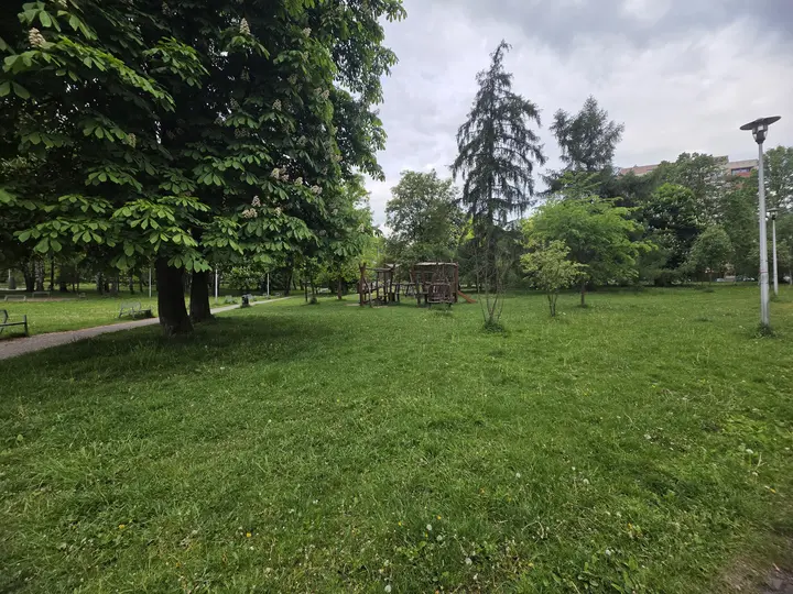 Widok placu zabaw z alei parkowej