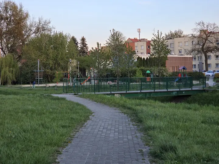 Widoczny plac zabaw za mostkiem