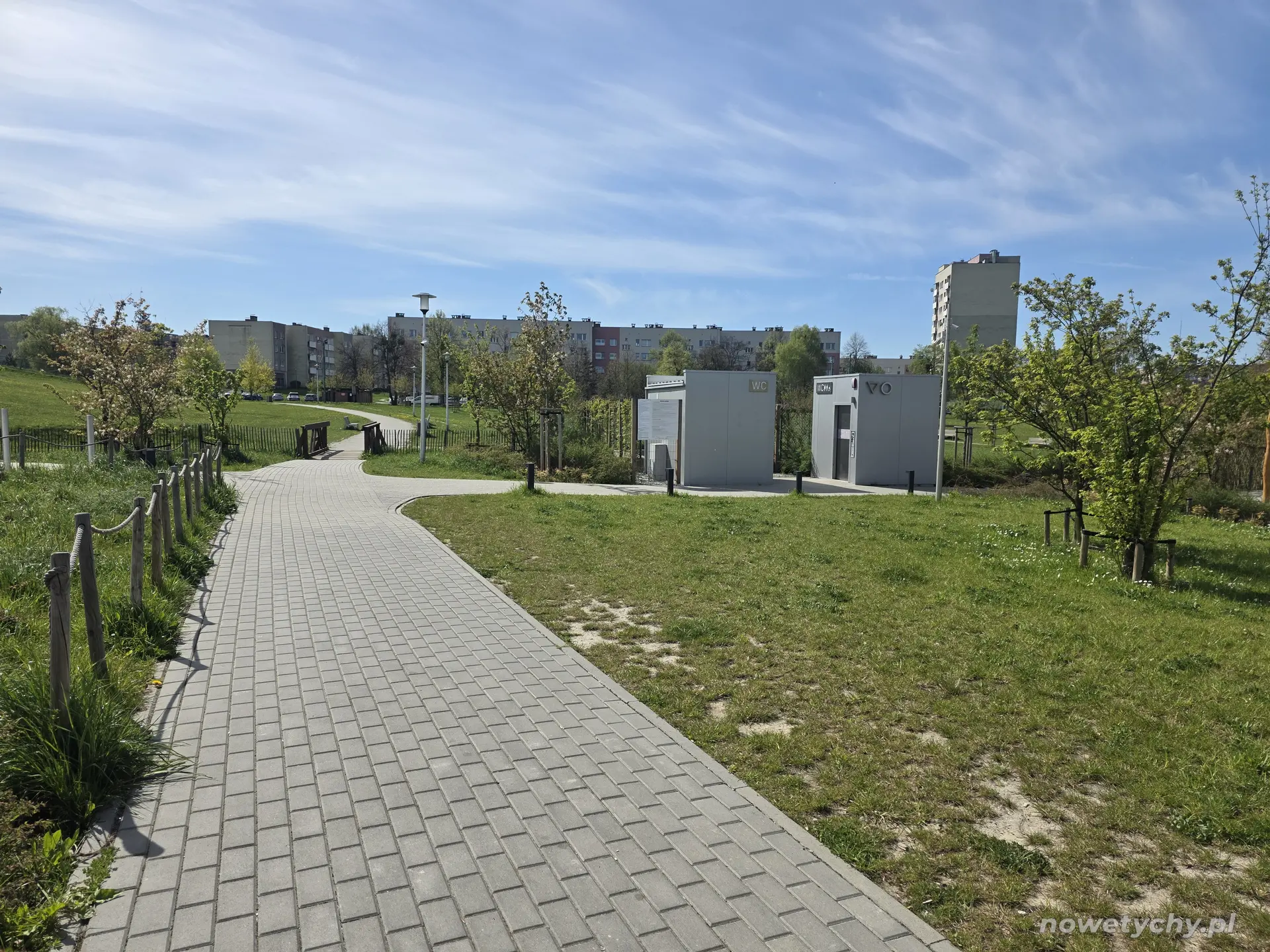 Parkowa alejka z toaletami publicznymi po prawej stronie