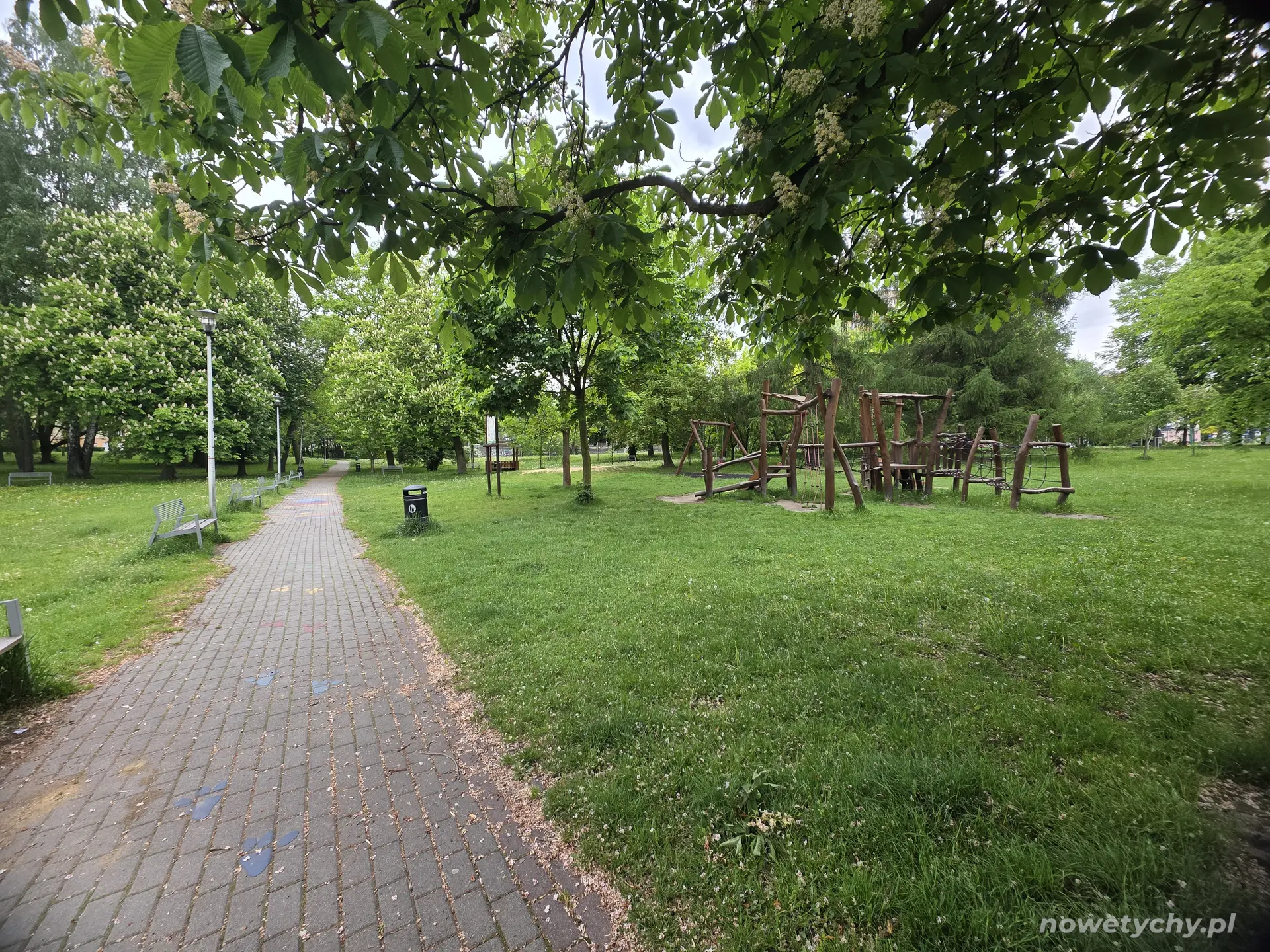 Po prawej stronie plac zabaw, na wybrukowanej alei kolorowe gry i zabawy dla dzieci
